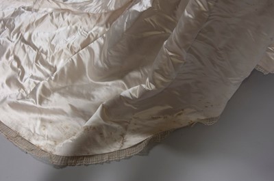 Lot 55 - An ivory satin bridal gown, late 1870s, of...