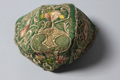 Lot 150 - An embroidered green satin baby cap, probably...